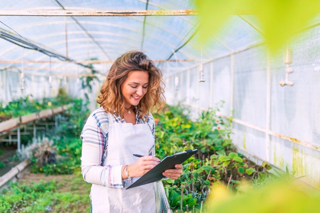 Woman holding clipboard in greenhouse