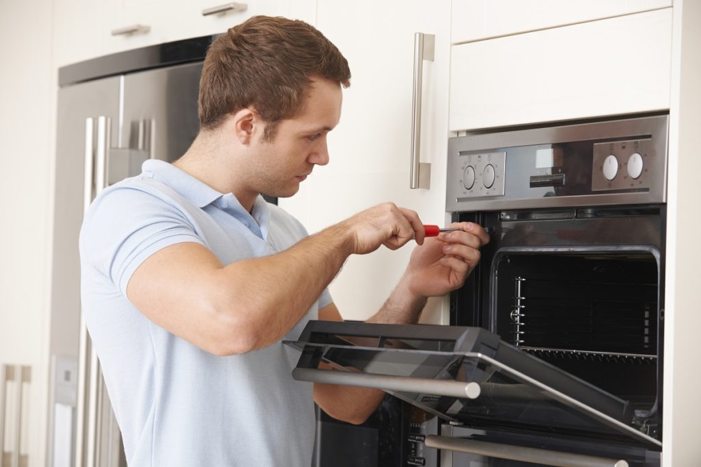 Man repairing an oven using a screw