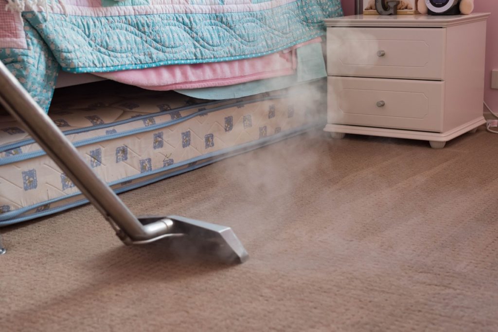 Steam vacuuming the bedroom carpet