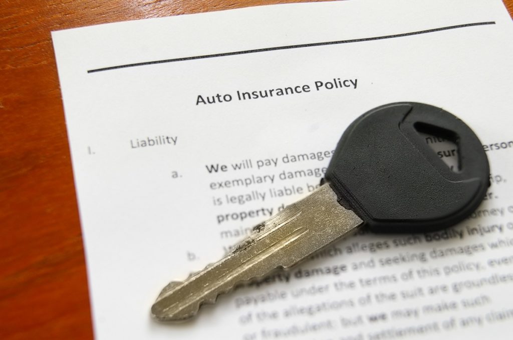 Auto insurance policy form with car key on top