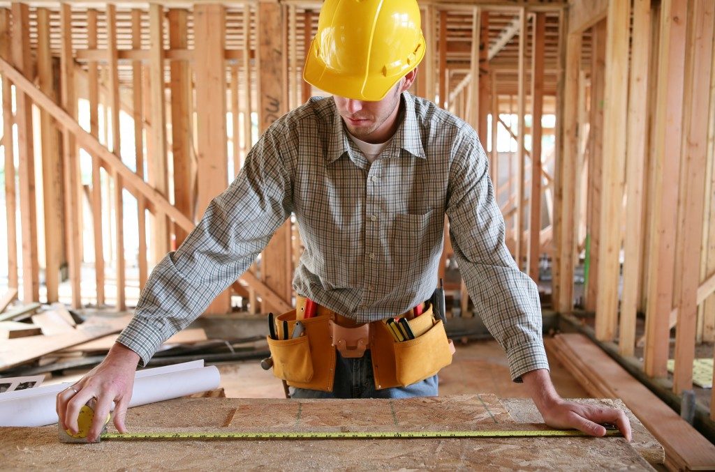 Man measuring plank in construction site