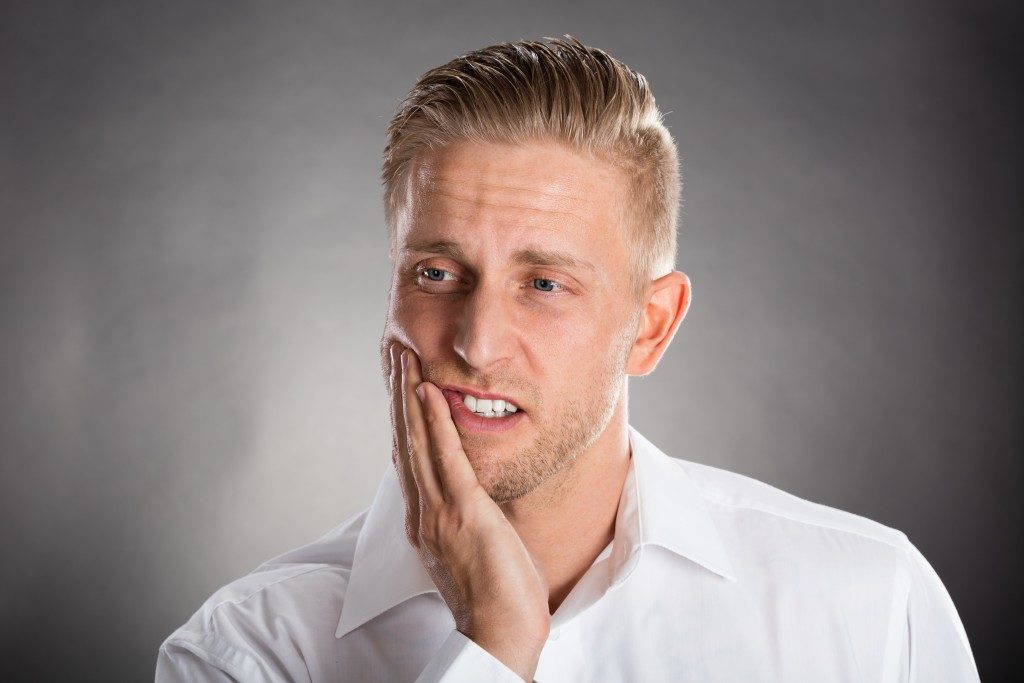 Man Suffering From Toothache Against Grey Background