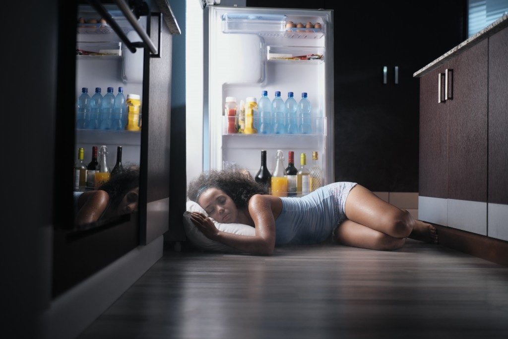 Woman sleeping infront an opened fridge