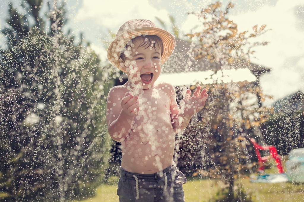 child playing in the sprinklers