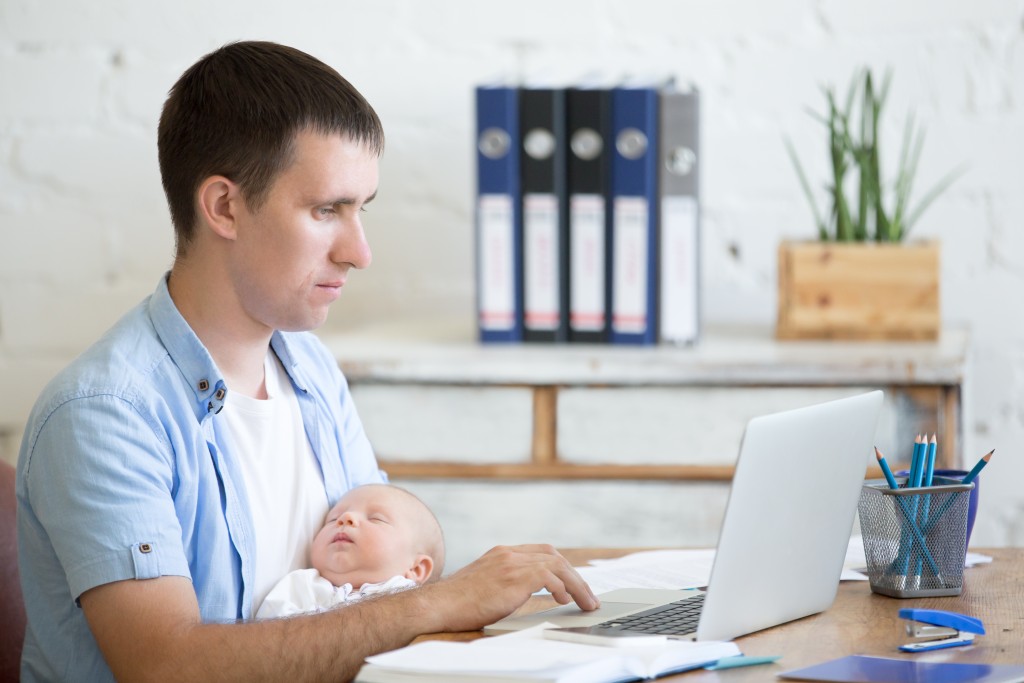 man working while holding child
