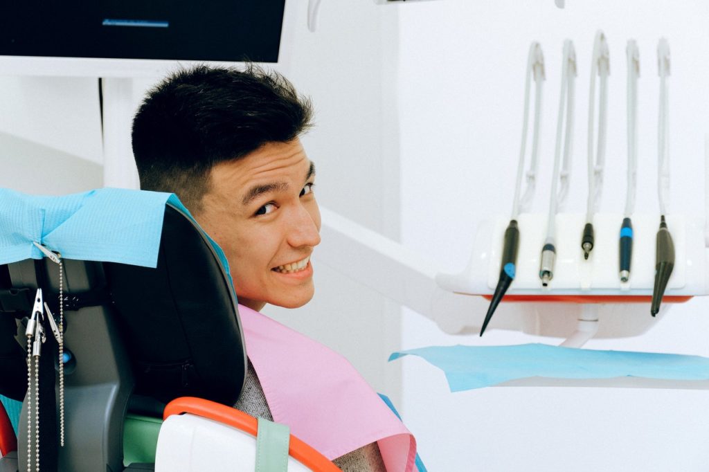 man sitting at the dentist's chair smiling looking back