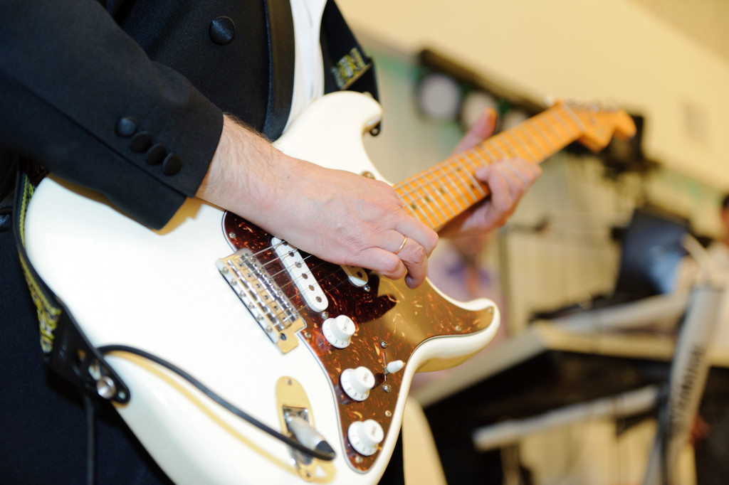 man playing a white electric guitar