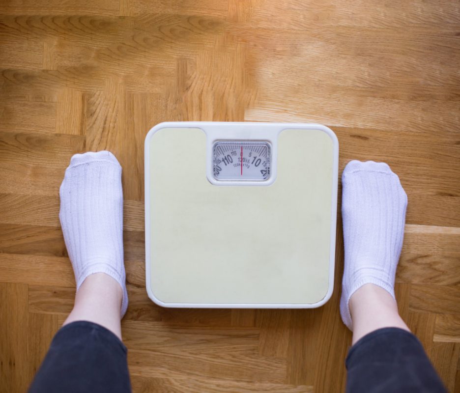 A person preparing to stand on a weighing scale