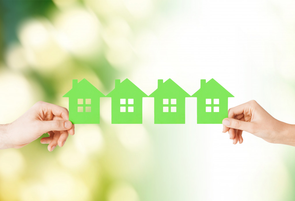 two hands holding a chain of green paper houses