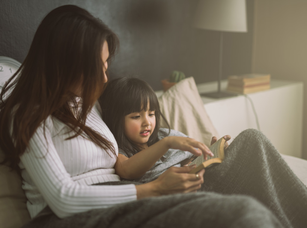 a mother reading a story to her daughter at bedtime