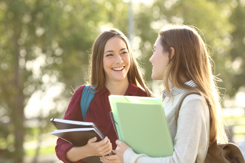 2 young women smiling while walking in a university with school requirements