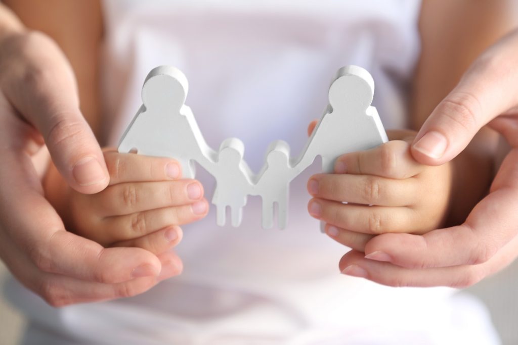 An adult and child's hands holding cutout of a family