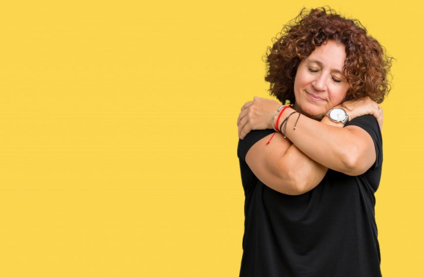 a middle aged woman hugging herself showing happy emotions