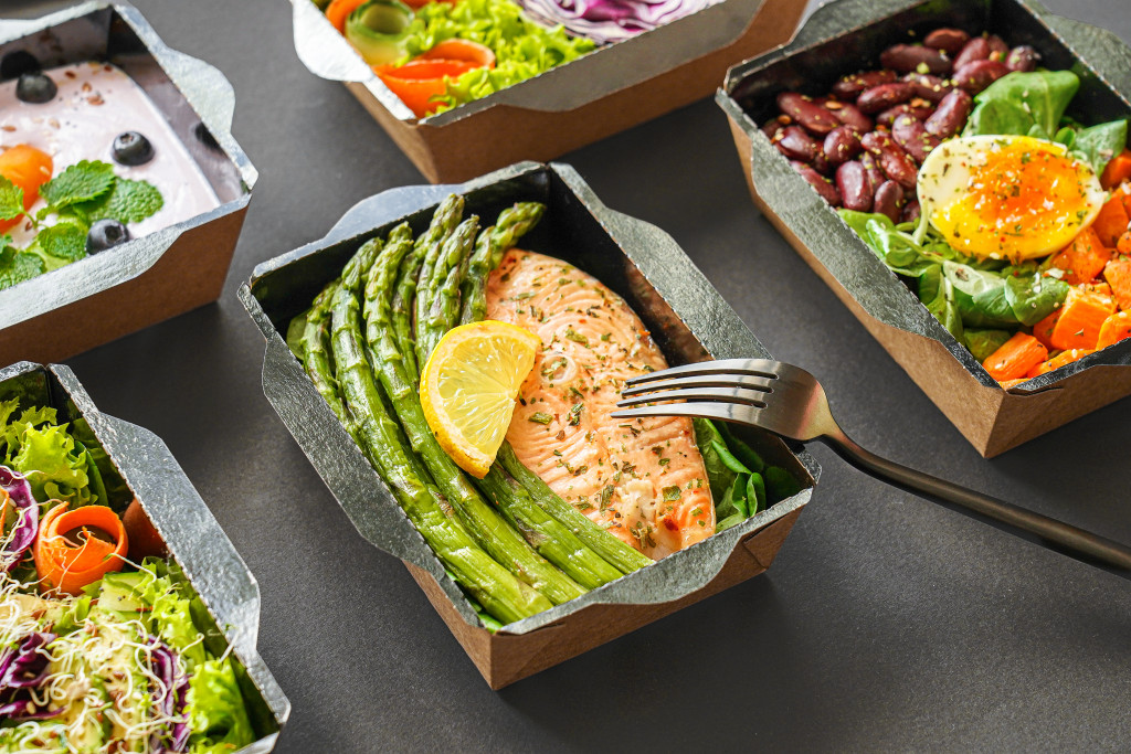 a picture of a ready-made food in a box consists of fish, lemon, and vegetables