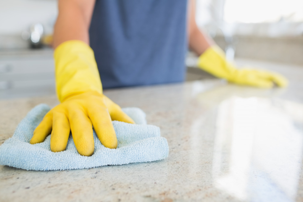 A person with rubber gloves wiping the kitchen counters